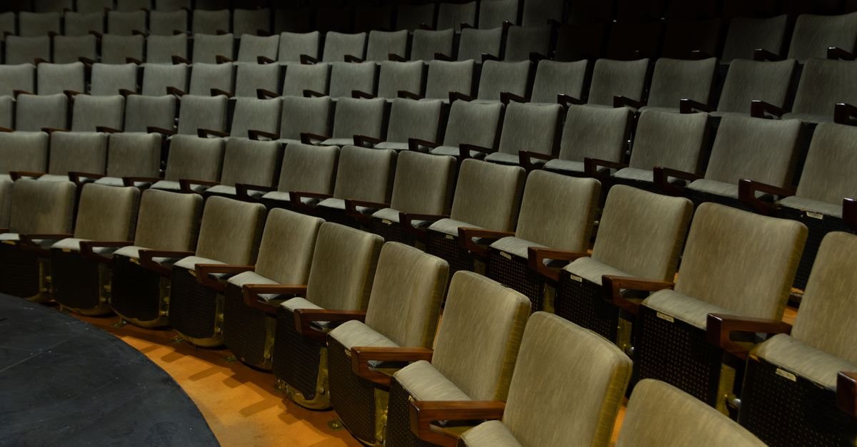 Fileiras de poltronas vazias em plateia de teatro