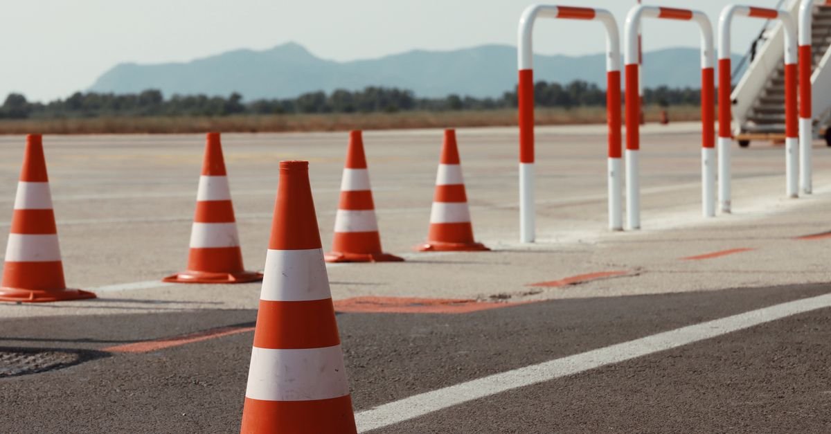Cones laranja de sinalização dispostos sobre pista asfaltada