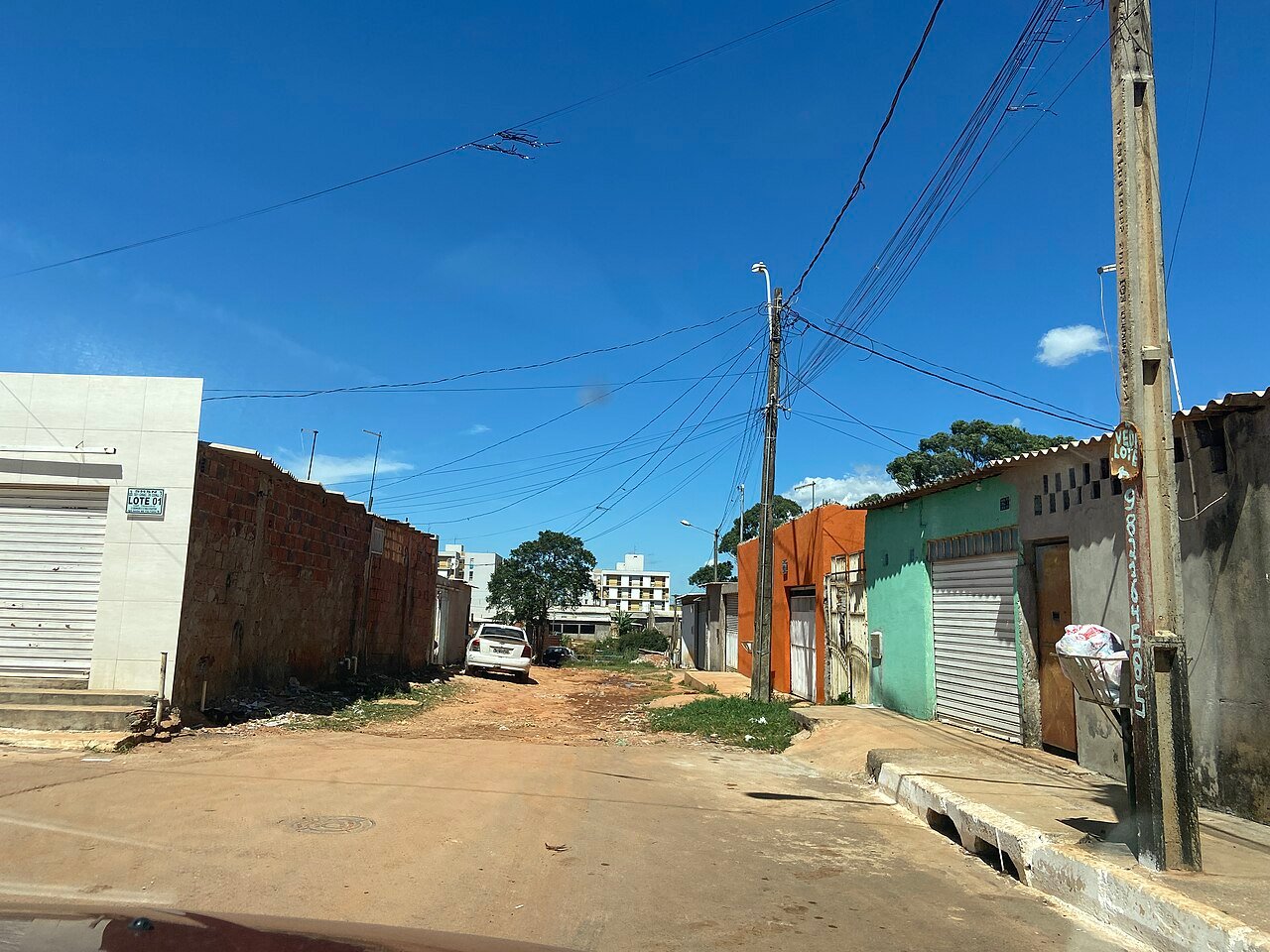 Rua do Trecho 01 do Sol Nascente, com casas, postes e via de terra ao fundo