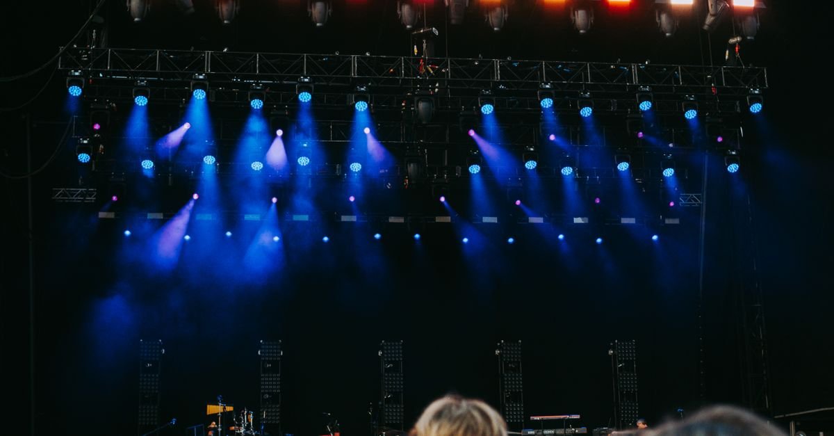 Palco de show iluminado por refletores azuis com público de costas