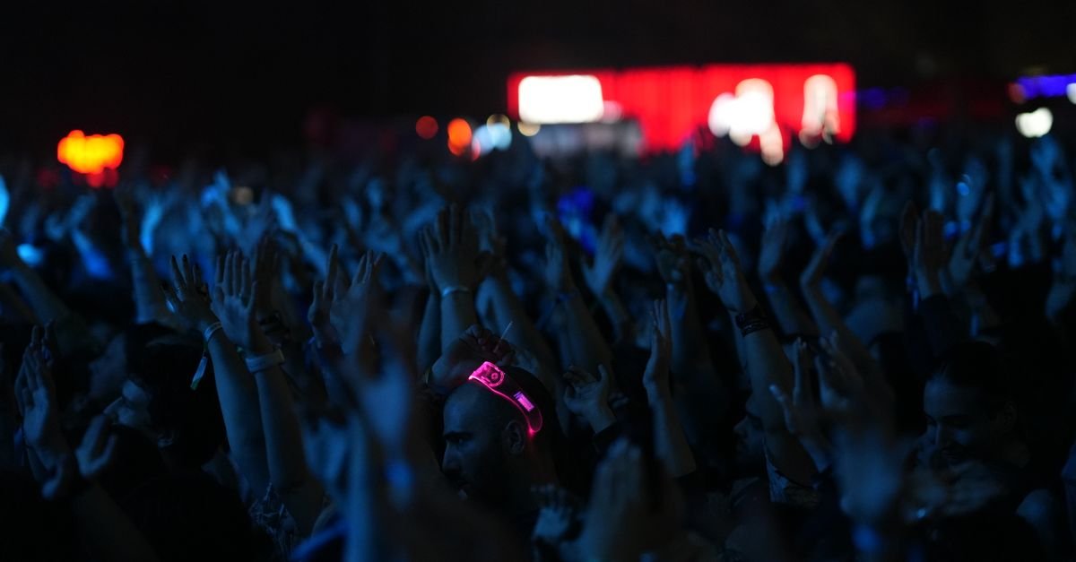 Publico de maos levantadas em show ao ar livre a noite