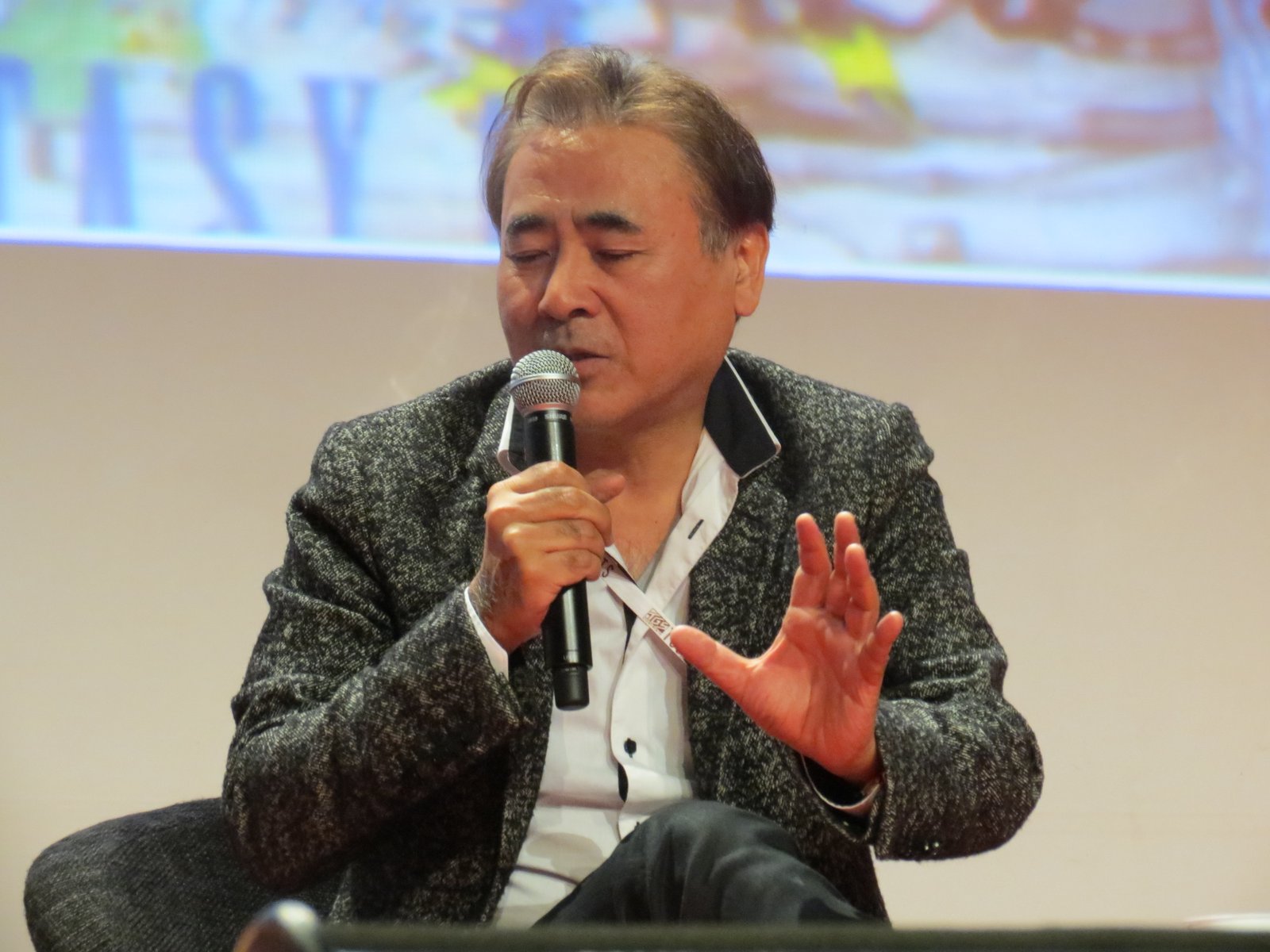 Yoshitaka Amano falando ao microfone num painel