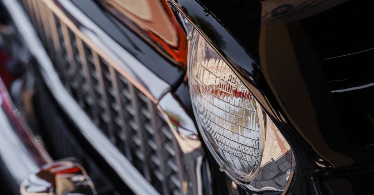 Detalhe do farol e da grade cromada de um carro antigo preto