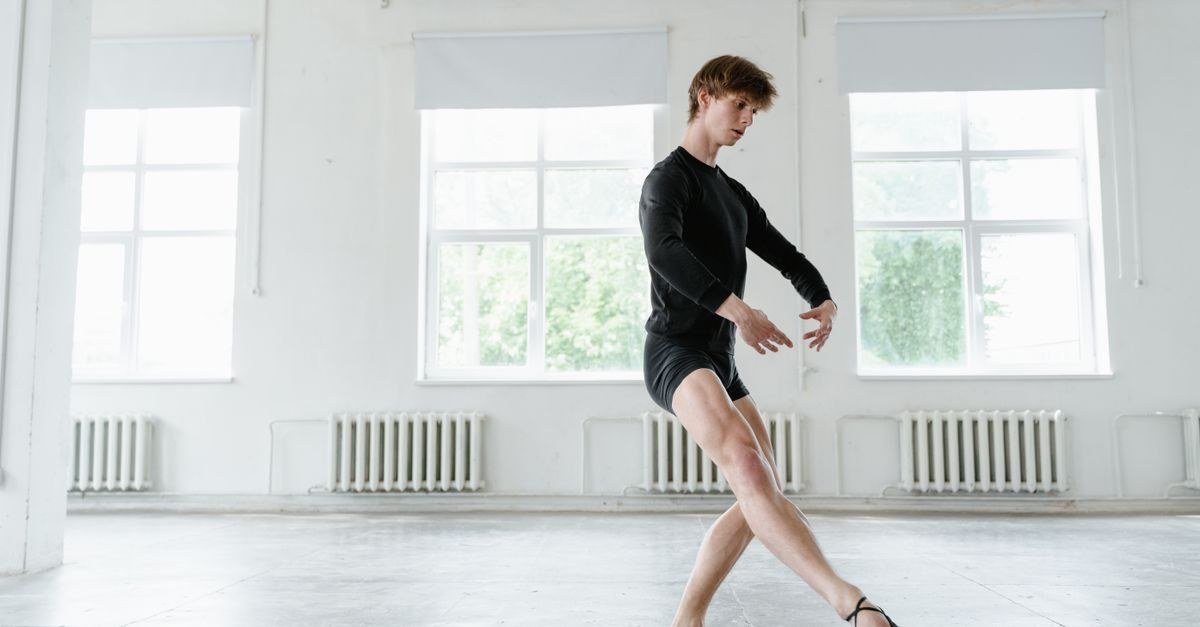 Bailarino em sala de ensaio de ballet clássico, com sapatilha, durante treino em estúdio iluminado