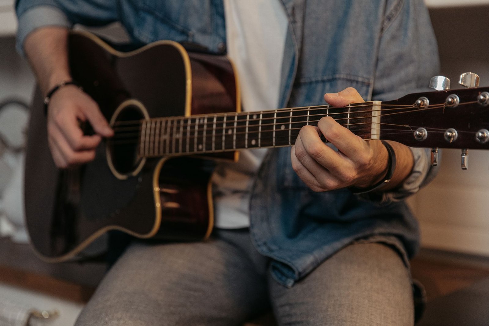 Mãos de um músico dedilhando um violão acústico (foto ilustrativa de banco de imagens)
