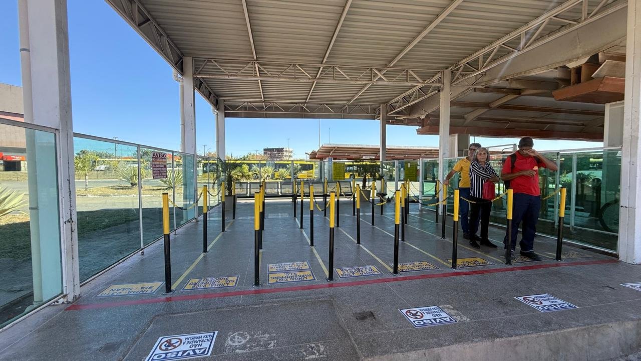 Plataforma de terminal do BRT com balizadores, correntes e decalques no piso indicando as linhas de onibus