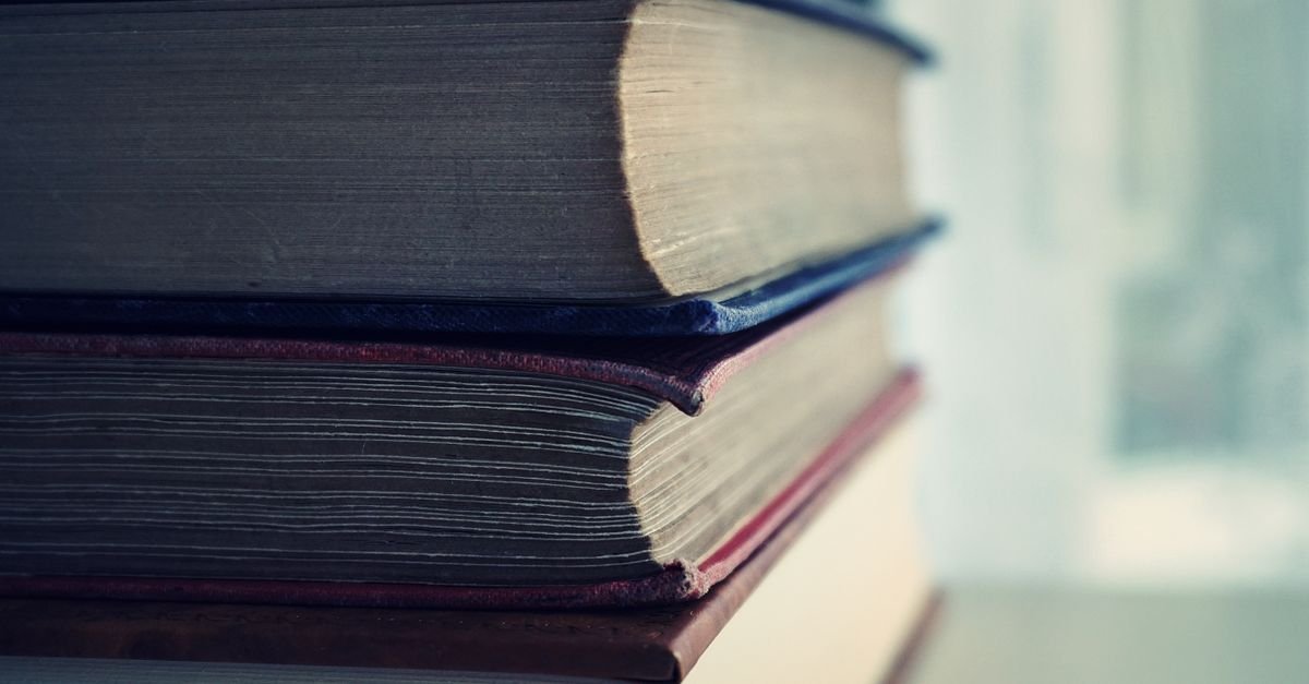 Pilha de livros de capa dura vistos de perto, com as páginas em foco e fundo desfocado