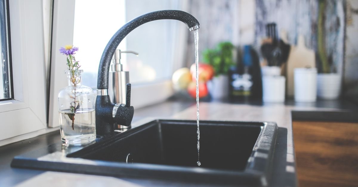 Torneira de cozinha com agua corrente sobre pia preta