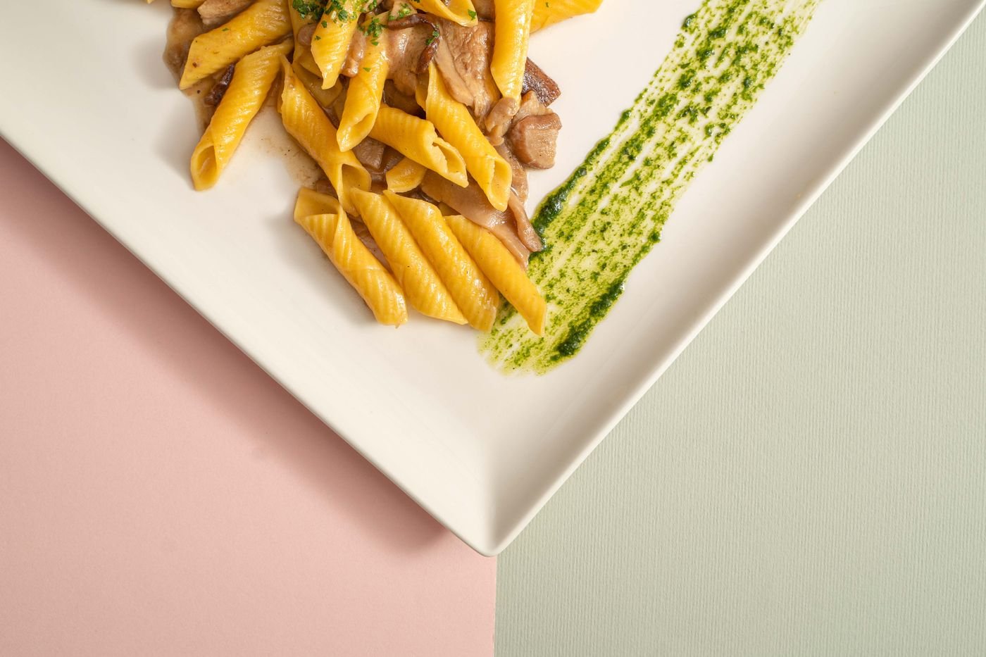 Prato de massa penne com cogumelos e pesto em prato branco