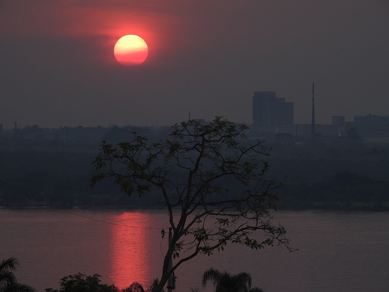 Fim de tarde no Lago Paranoá, com o sol baixo refletido na água e a silhueta da cidade ao fundo