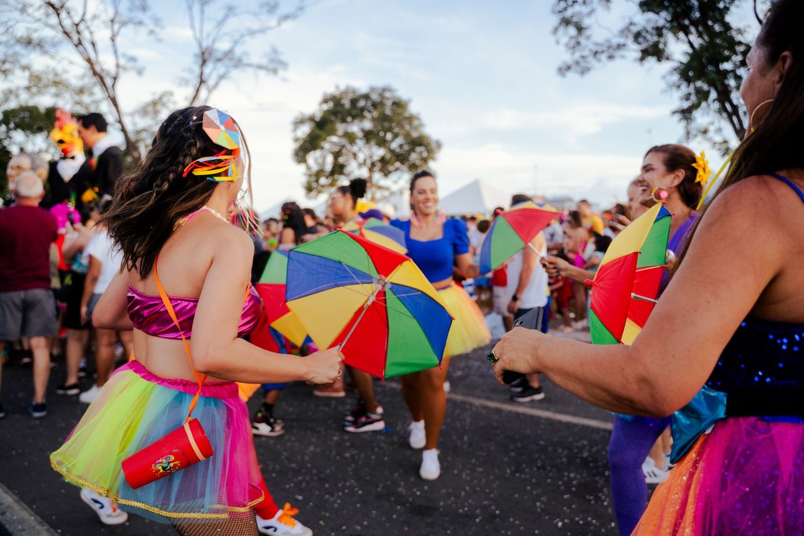 Foliões dançam com sombrinhas coloridas em bloco de carnaval de rua em Brasília