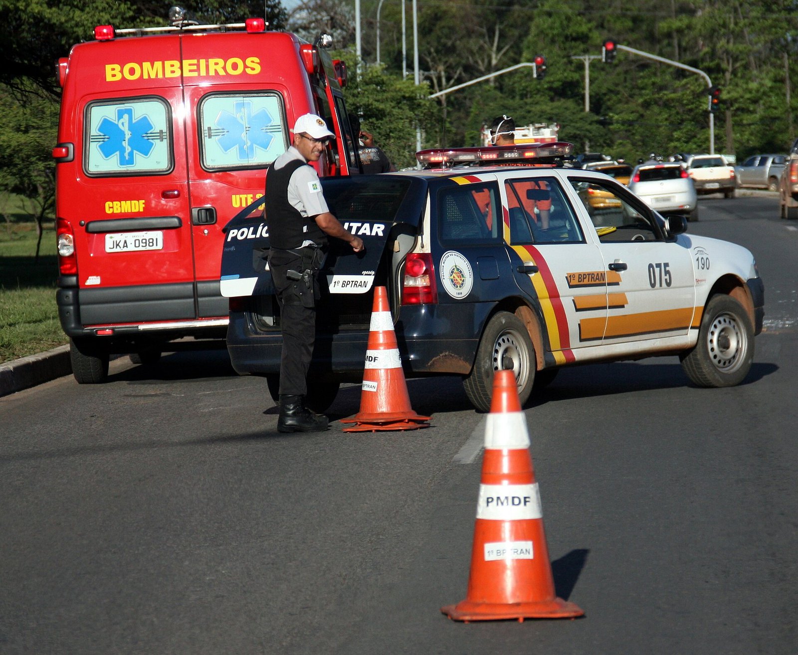 Viatura de resgate do Corpo de Bombeiros do Distrito Federal e carro do 1º BPTran da Polícia Militar em atendimento de ocorrência de trânsito em via de Brasília, com cones no asfalto