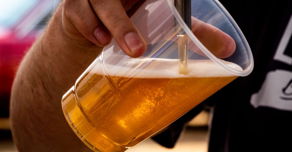 Copo plástico sendo enchido com cerveja artesanal em festival ao ar livre