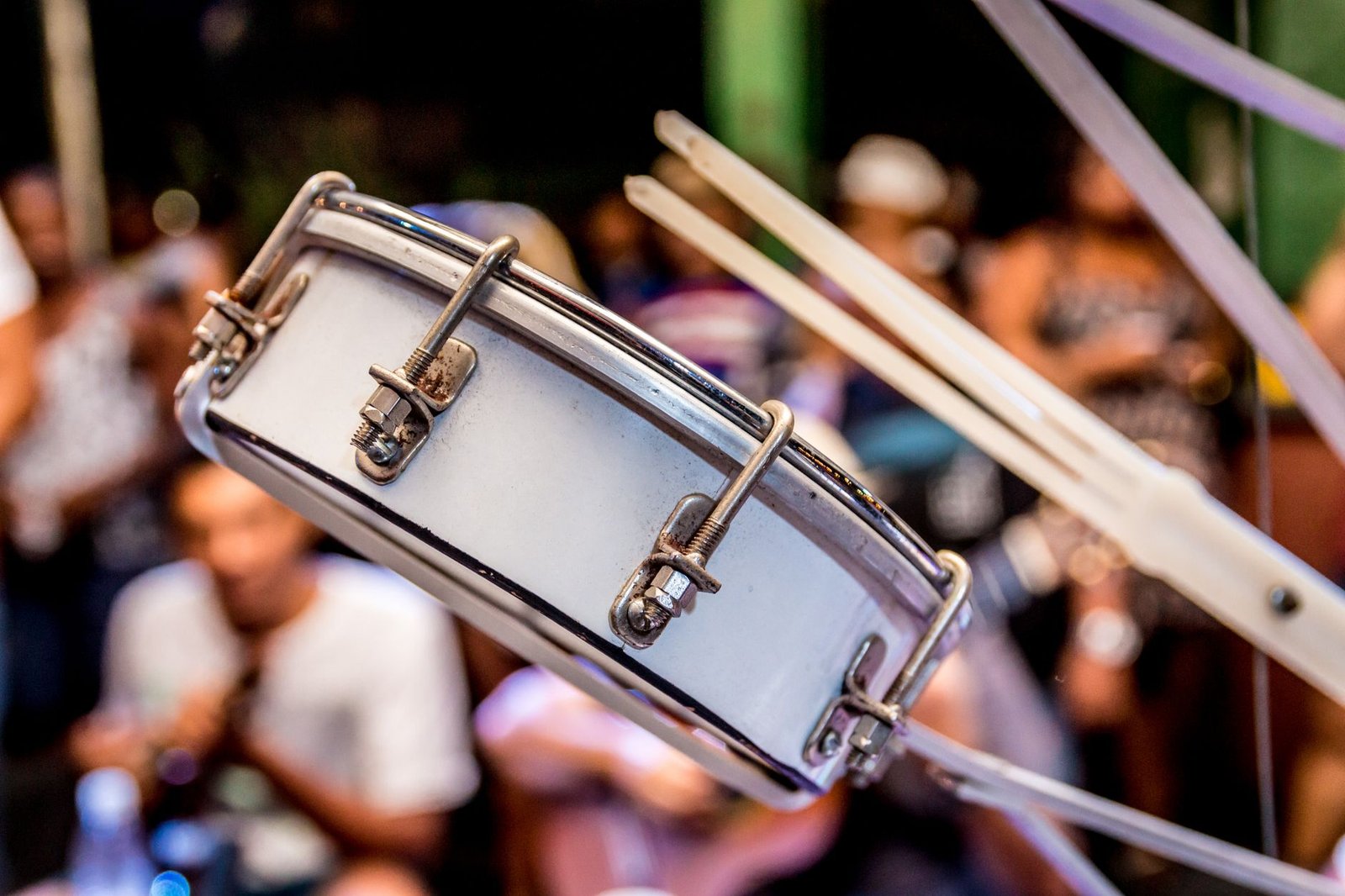 Surdo de samba em primeiro plano com a plateia desfocada ao fundo