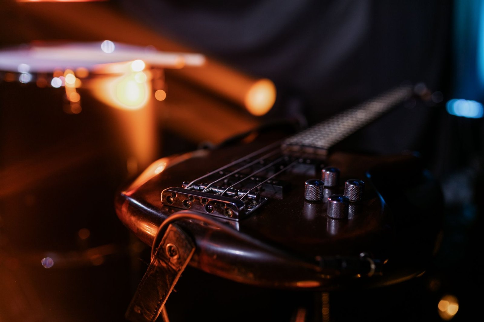 Guitarra elétrica apoiada em palco de bar, com luzes quentes desfocadas ao fundo