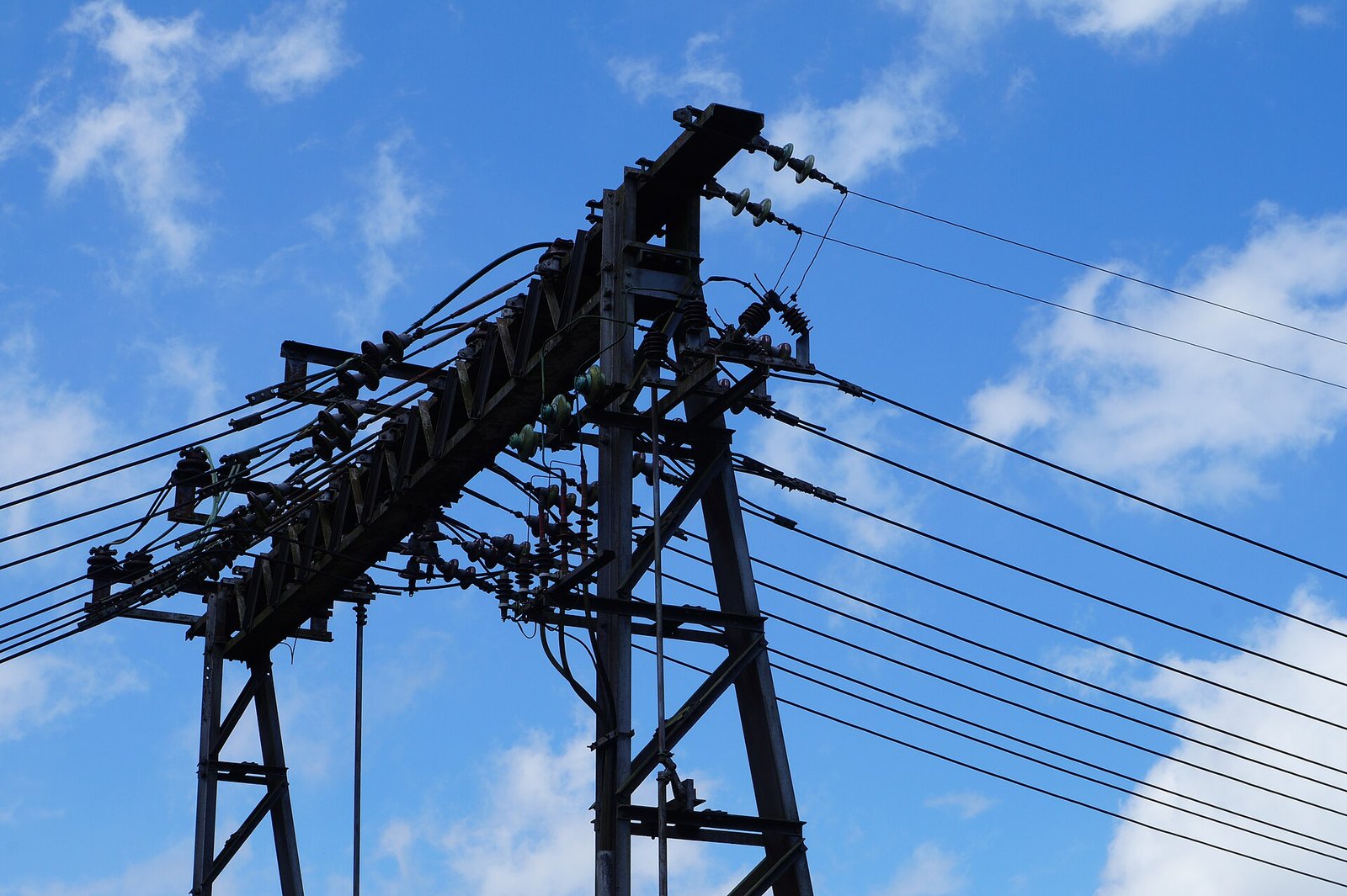 Poste de distribuição de energia elétrica com isoladores e cabos contra céu azul
