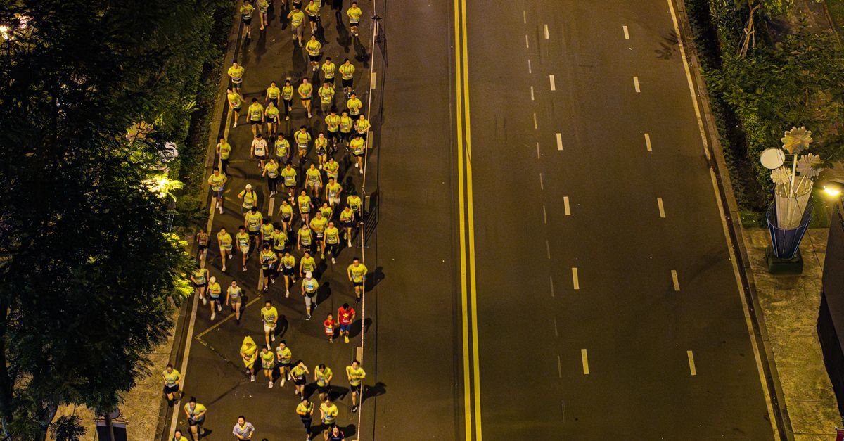 Vista aérea de corredores em prova de rua noturna em avenida urbana