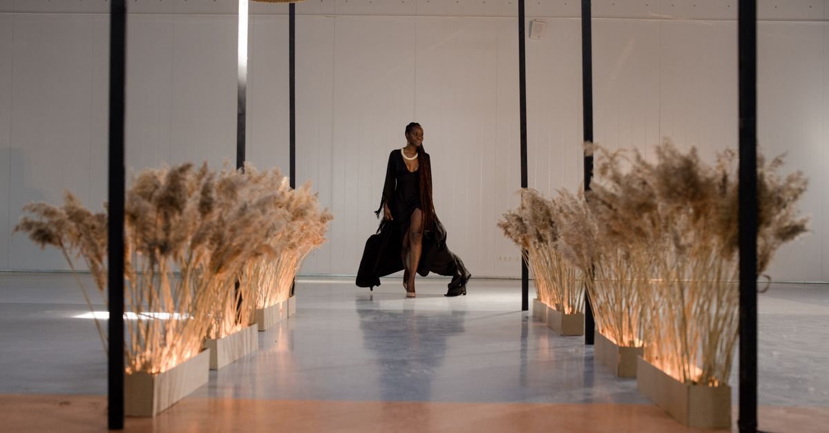 Modelo caminha por passarela de desfile com vestido longo preto