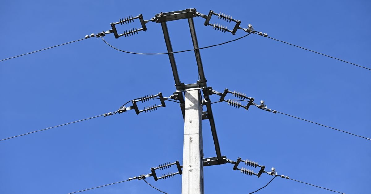 Poste da rede elétrica com isoladores e fios contra o céu azul