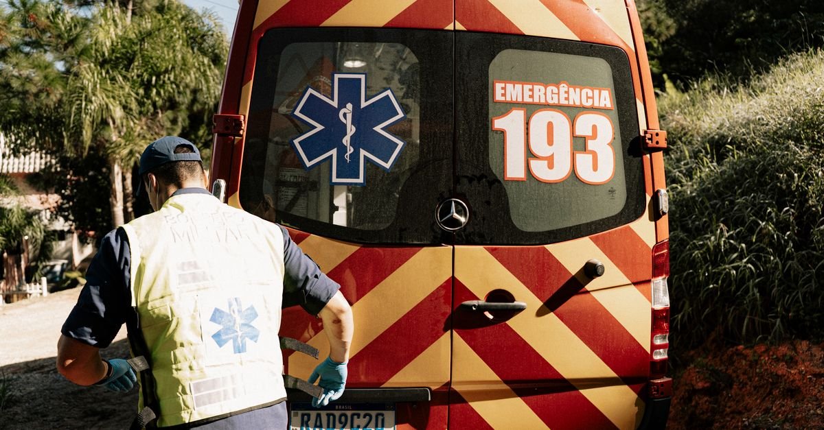 Socorrista ao lado da traseira de ambulância brasileira com a inscrição Emergência 193