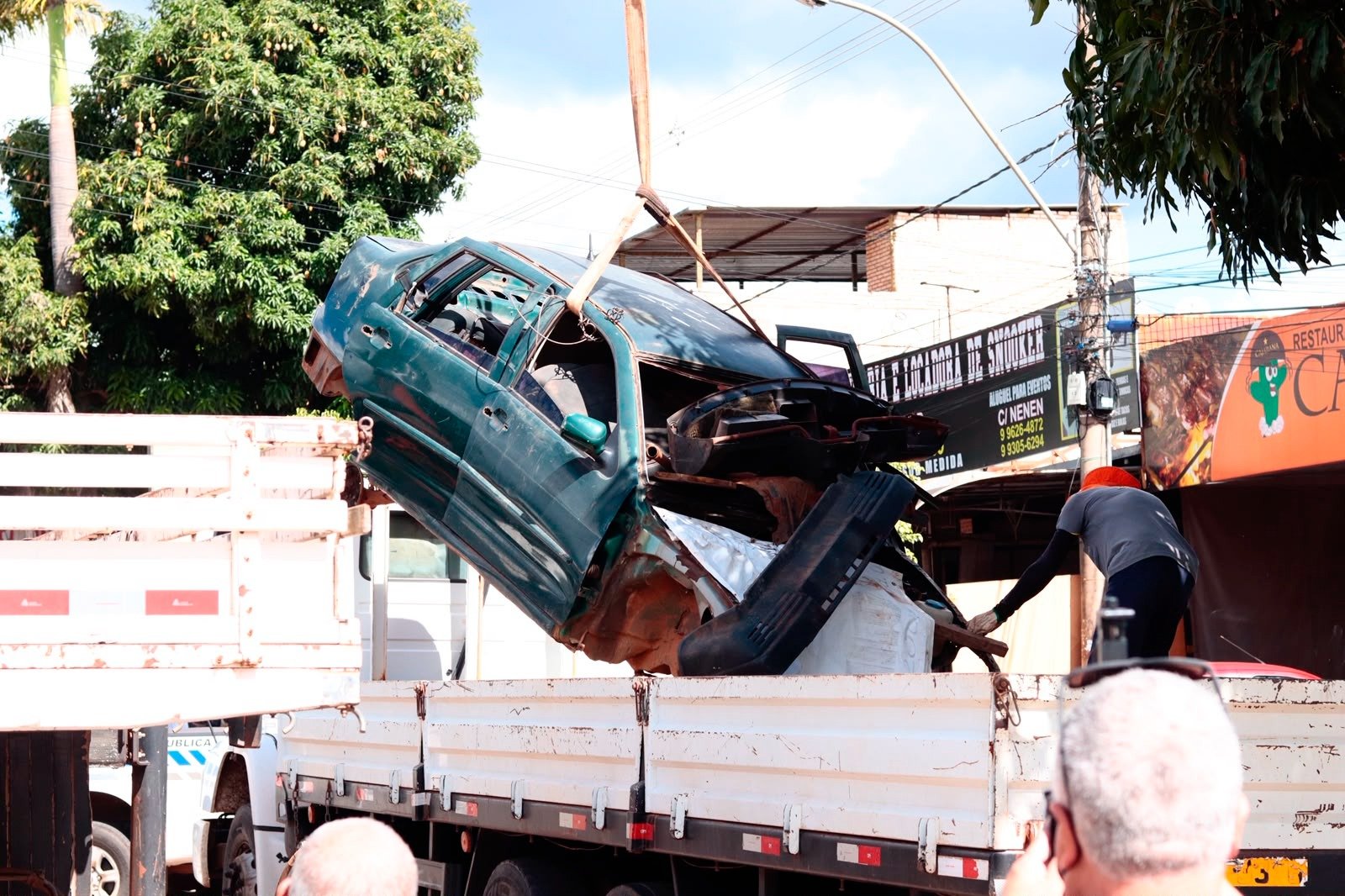 Guindaste ergue carcaça de carro para a carroceria de um caminhão durante operação de recolhimento no DF