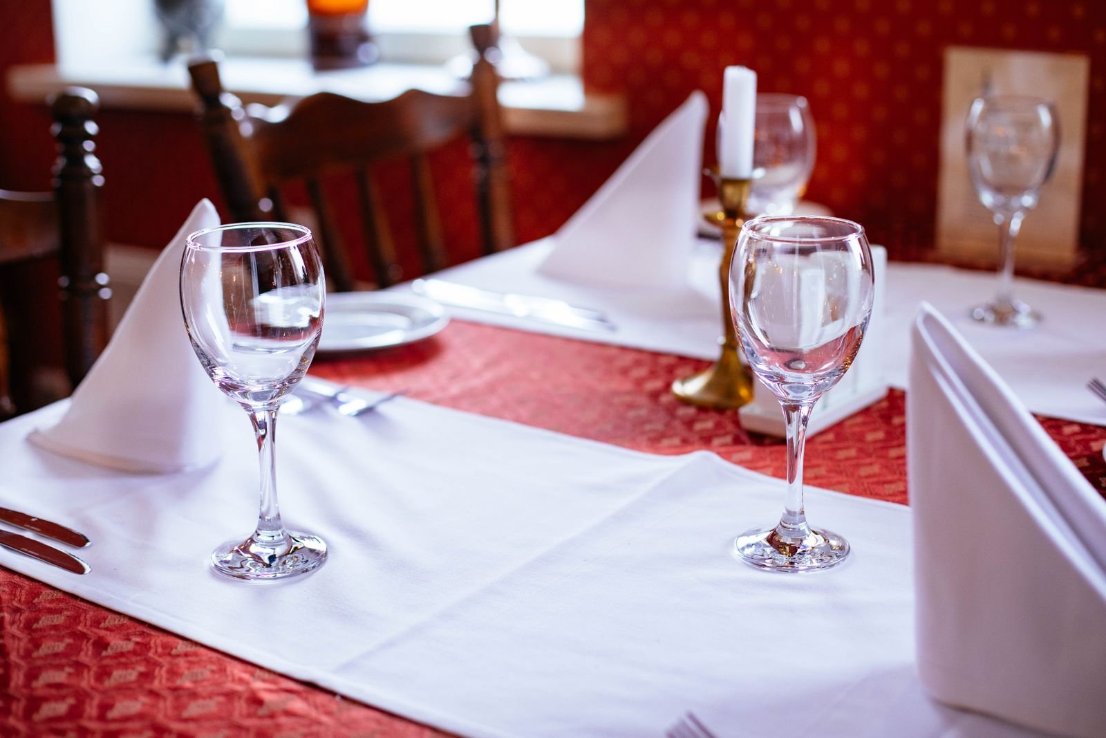 Mesa de restaurante posta com taças de vinho e guardanapos