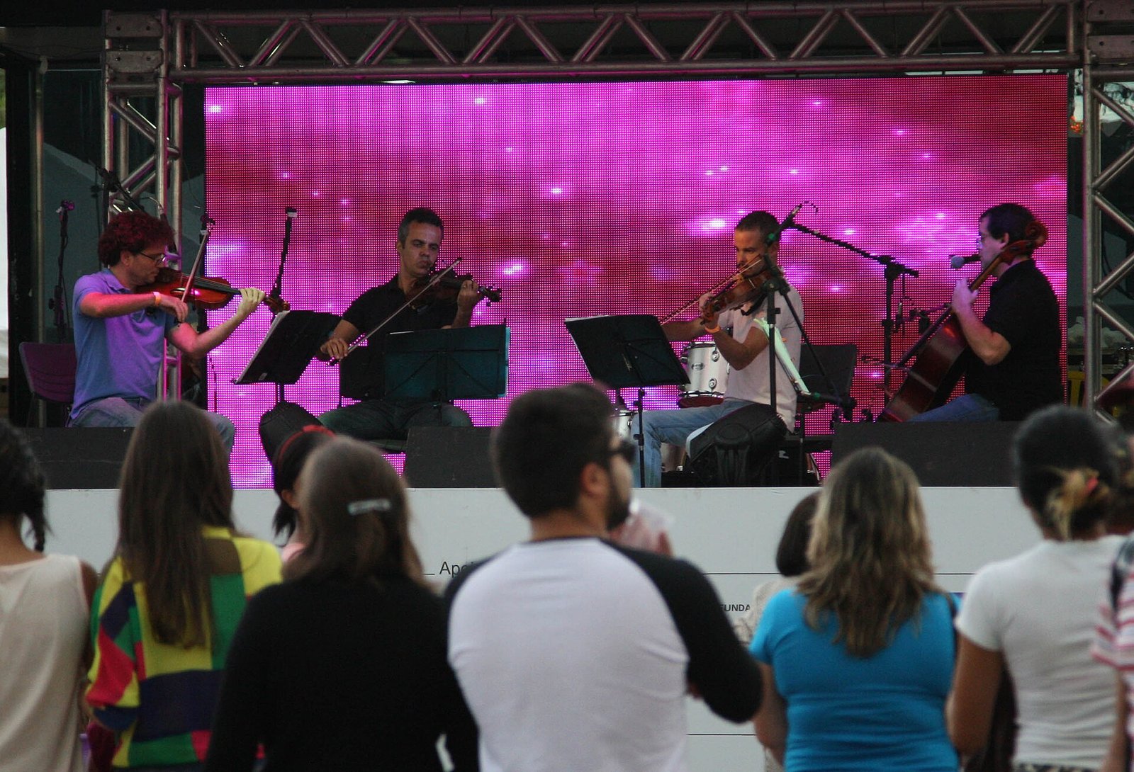 Quarteto de cordas se apresenta em palco ao ar livre para plateia em Brasília