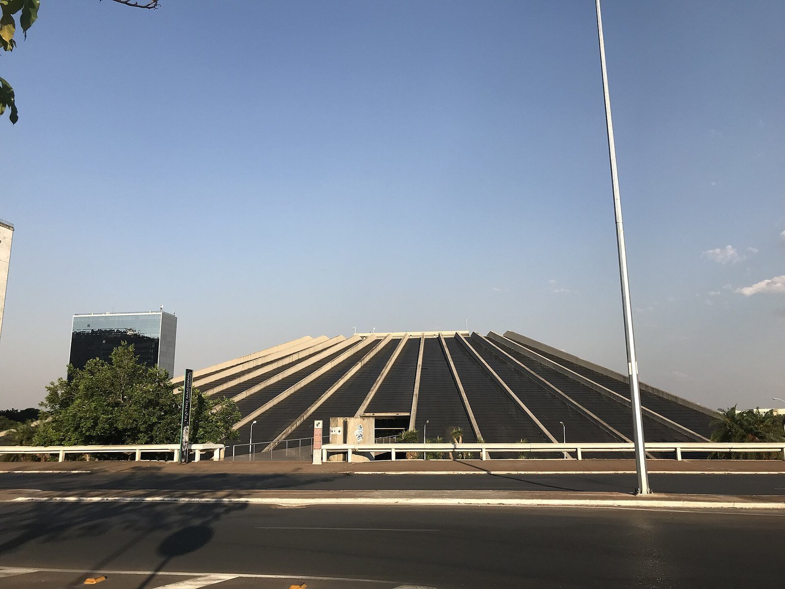 Fachada em pirâmide do Teatro Nacional Cláudio Santoro vista da via, com a placa do teatro à esquerda