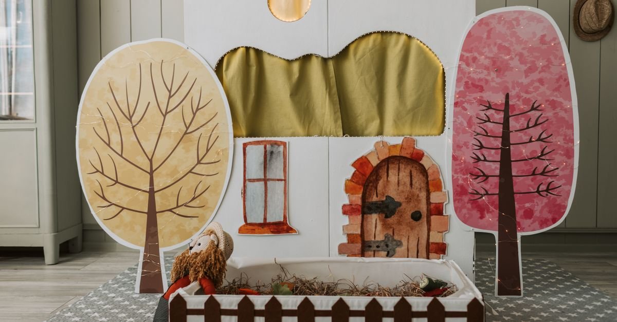 Cenario de teatro de bonecos montado com arvores de papel e casinha pintada