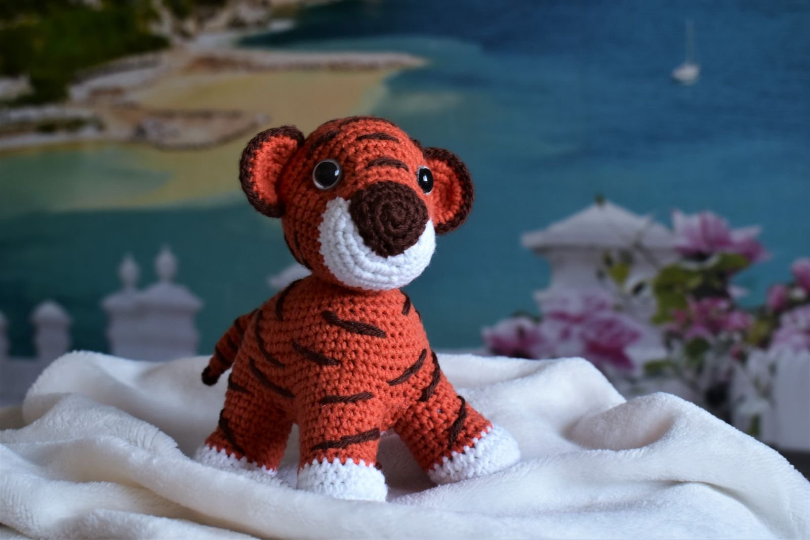 Bichinho de croche feito a mao, do tipo amigurumi, apoiado sobre tecido claro