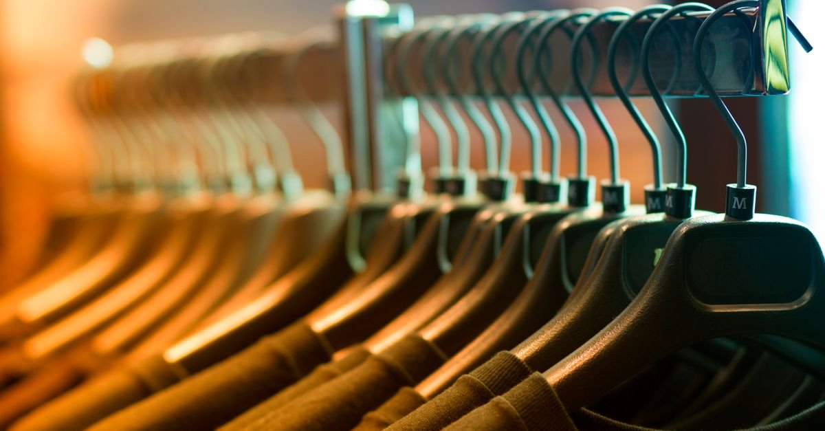 Arara de roupas com peças penduradas em cabides de madeira em loja