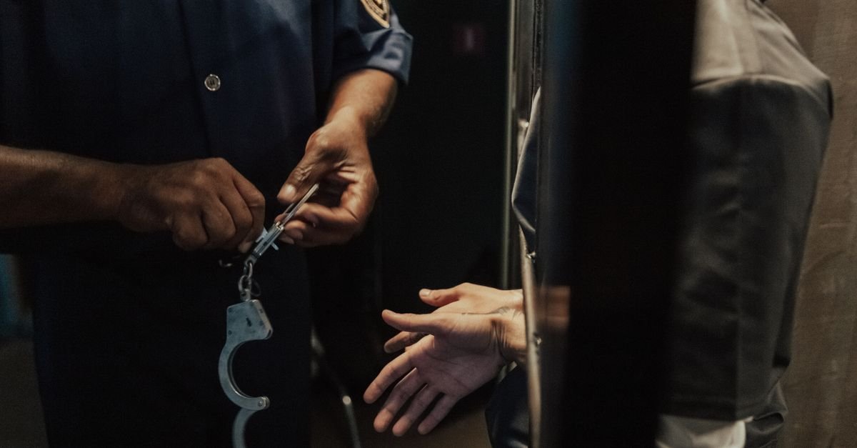 Agente segura algemas diante da porta de uma cela