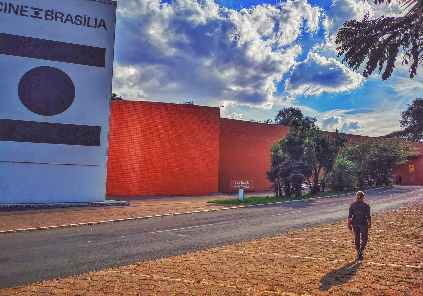 Fachada de tijolo vermelho do Cine Brasília com painel do logotipo em dia de céu azul