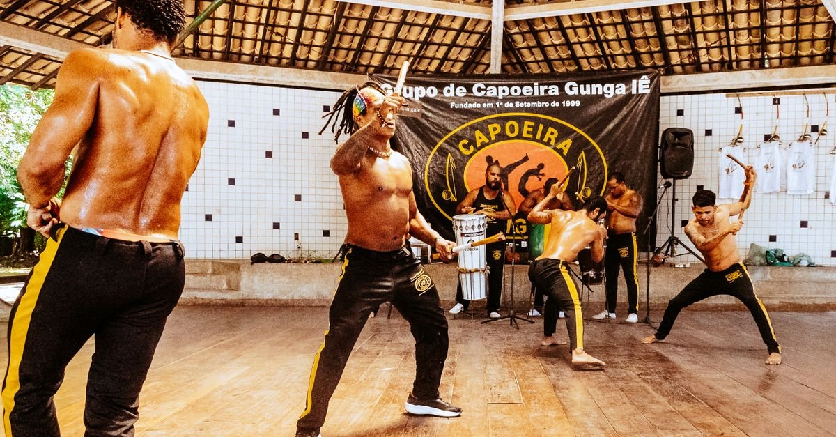 Roda de capoeira com músicos tocando atabaque durante apresentação ao ar livre