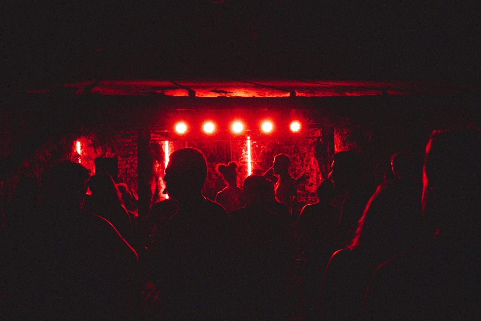 Plateia em silhueta diante de um palco com luzes vermelhas durante um show de rock