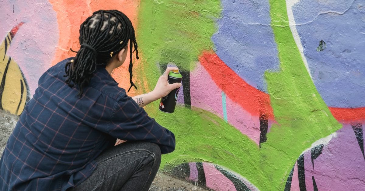Artista pintando mural colorido de grafite com lata de spray