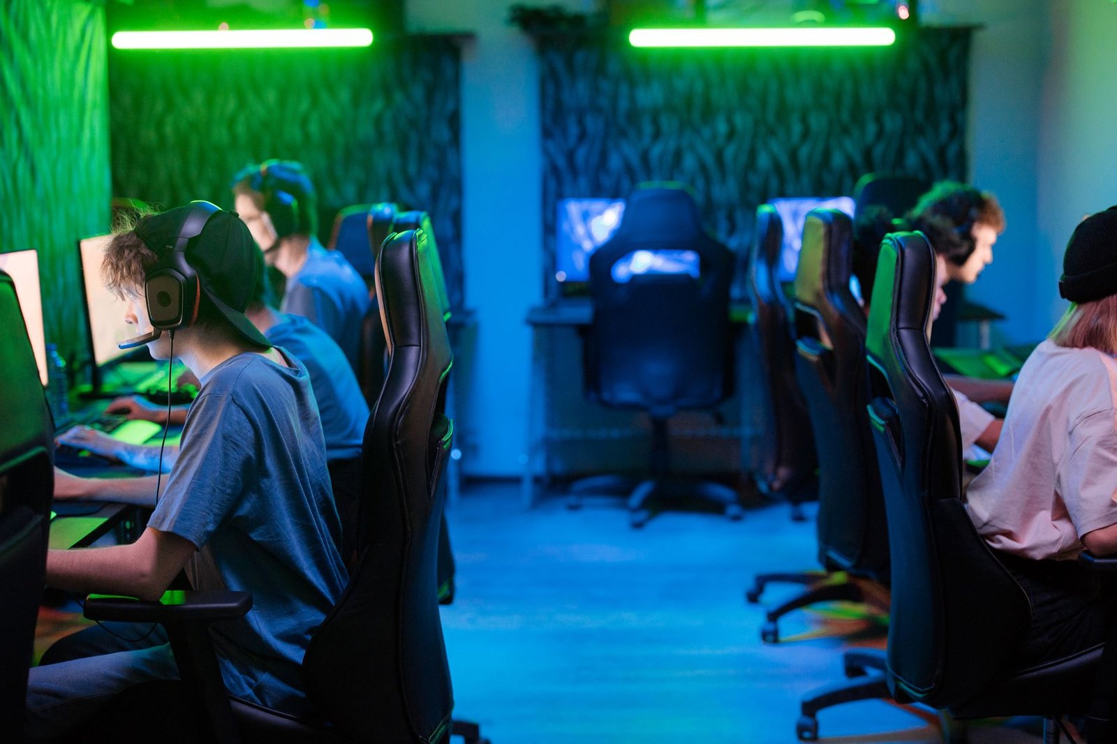 Jogadores em sala de computadores com iluminação verde e azul