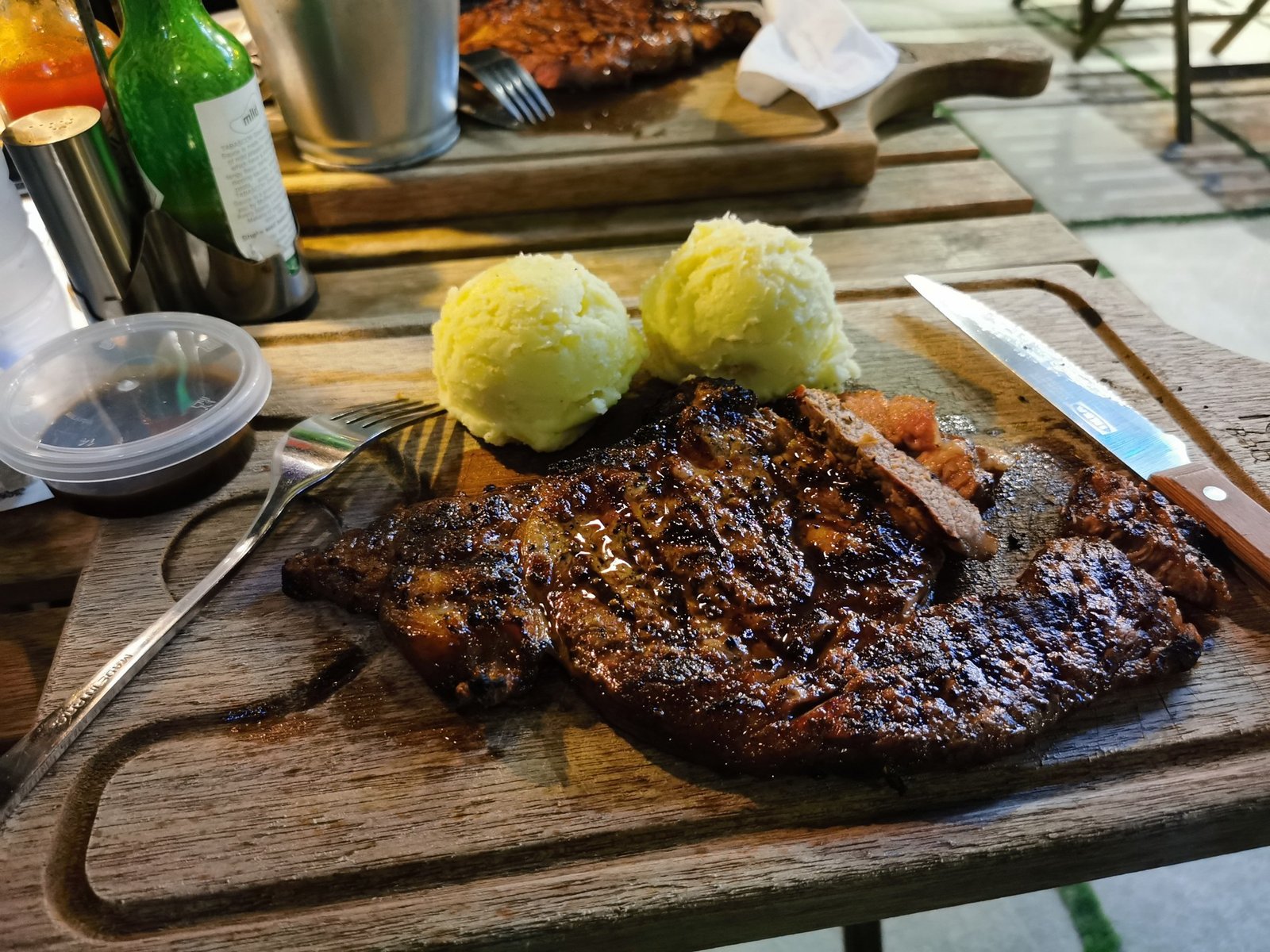 Bife grelhado com purê de batata em tábua de madeira, imagem ilustrativa de prato de carne