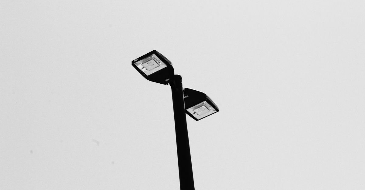 Poste de iluminação pública com duas luminárias de LED recortado contra o céu claro