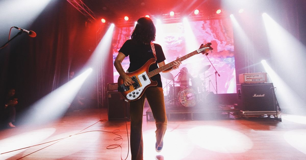 Músico toca baixo em palco iluminado durante show de rock