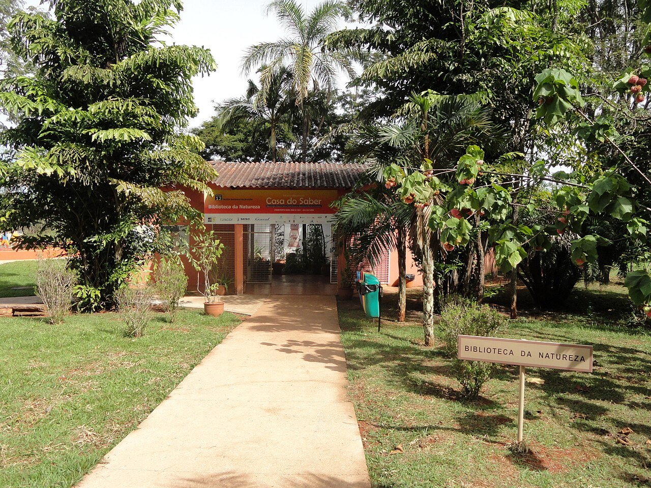 Entrada da Biblioteca da Natureza, espaço dentro do Jardim Botânico de Brasília, cercada por árvores e gramado