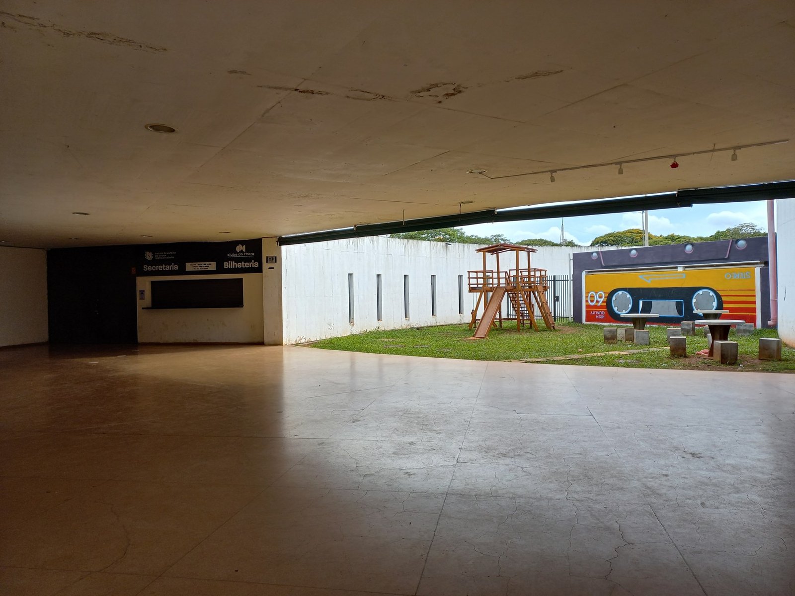 Hall do Clube do Choro com bilheteria e secretaria ao fundo e mural de fita cassete