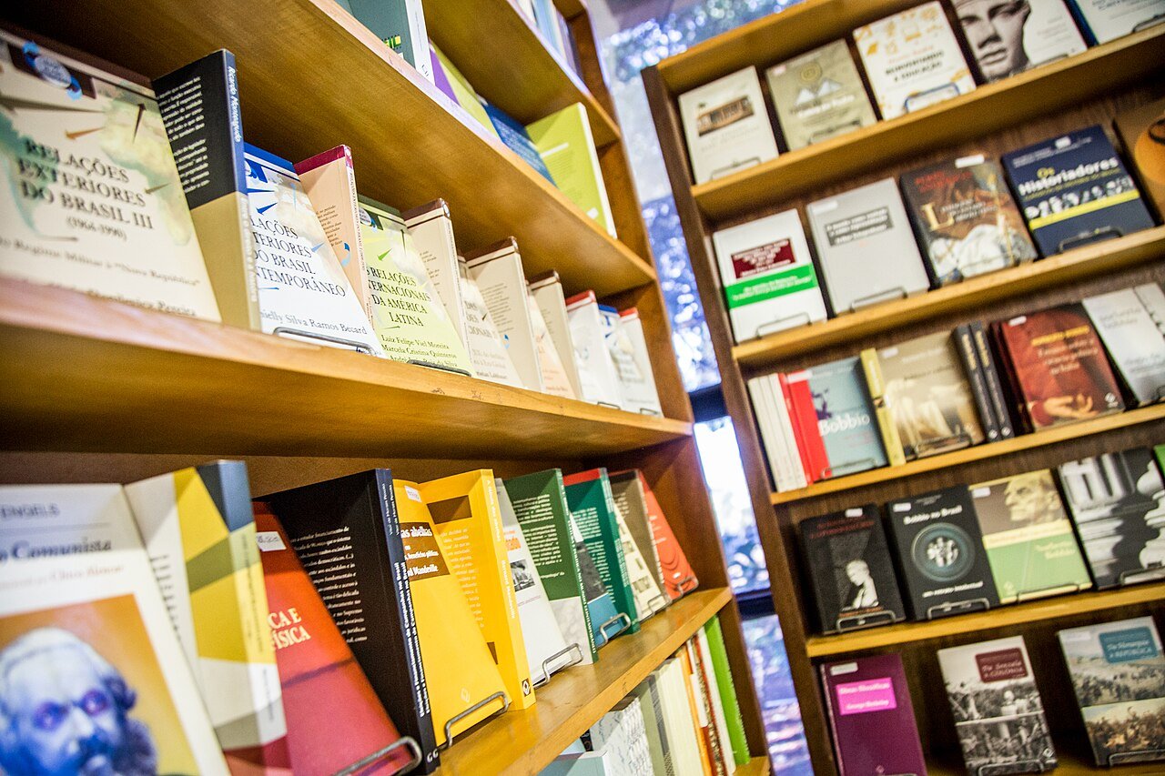 Estantes de madeira com livros de capas coloridas expostos em prateleiras de uma livraria
