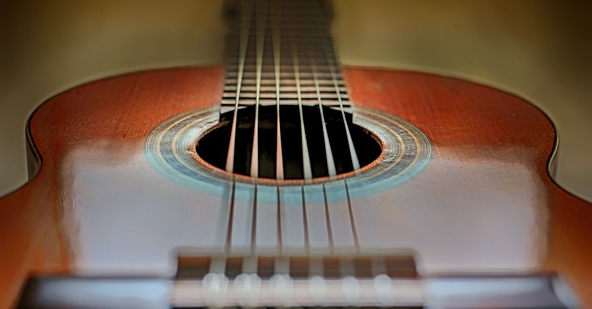 Close-up de um violão acústico clássico mostrando as cordas e a boca do instrumento