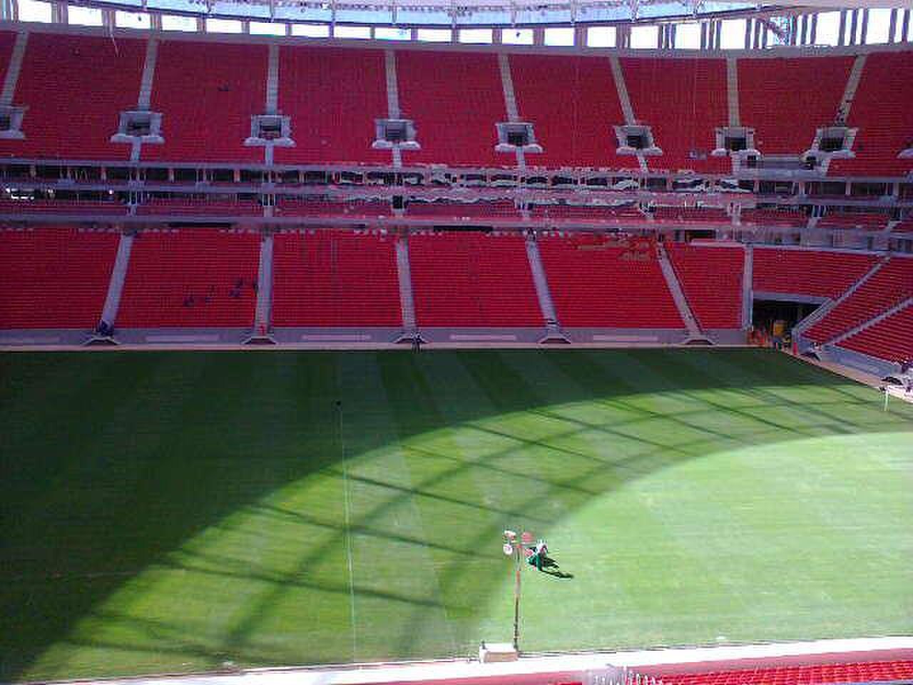 Vista interna da Arena BRB Mané Garrincha com gramado e arquibancadas vermelhas vazias