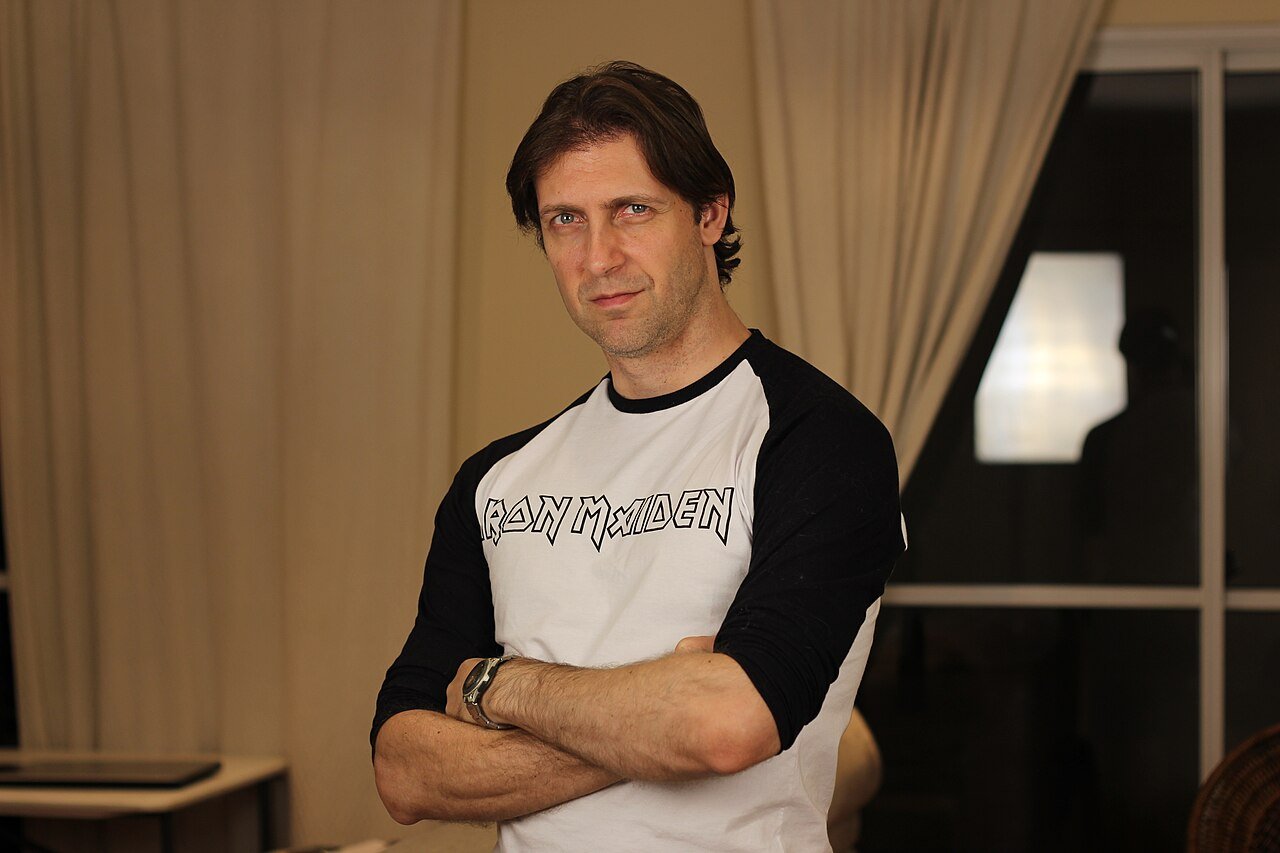 Bruno Sutter, intérprete do vocalista Detonator, de braços cruzados com camiseta do Iron Maiden