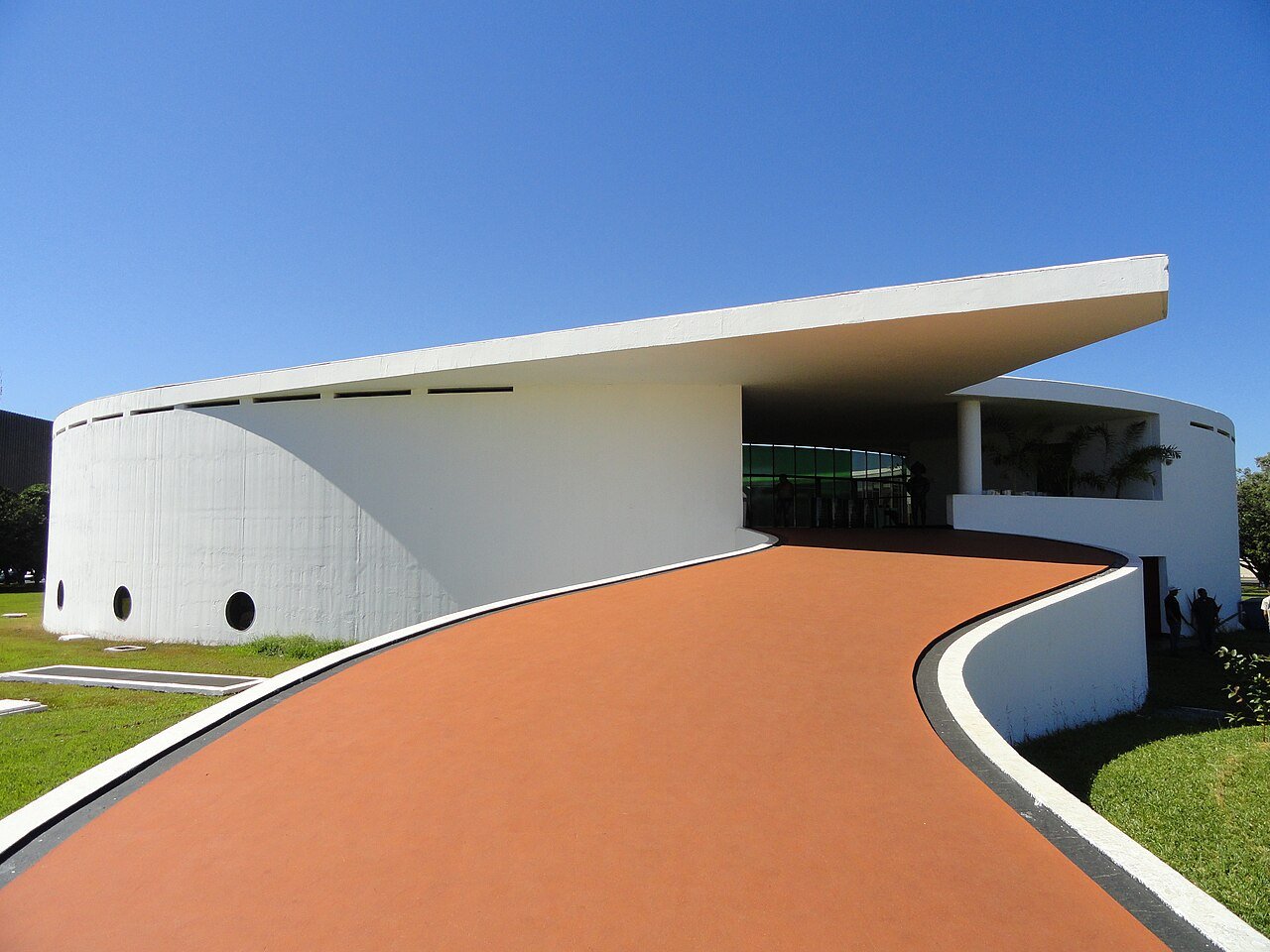 Rampa de acesso e fachada circular branca do Memorial dos Povos Indígenas, projeto de Oscar Niemeyer, em Brasília