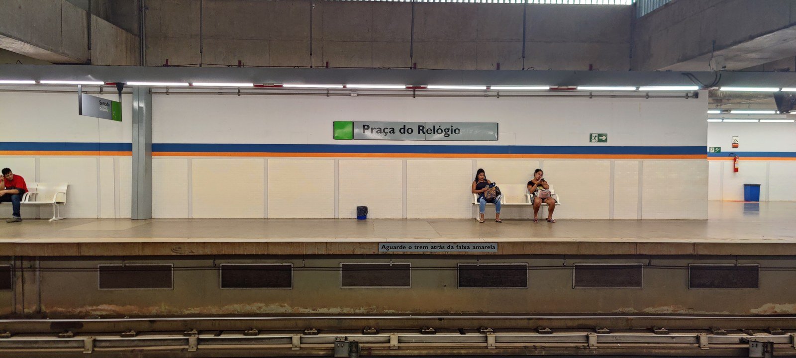 Plataforma da estação Praça do Relógio, vizinha da Onoyama, com passageiros sentados