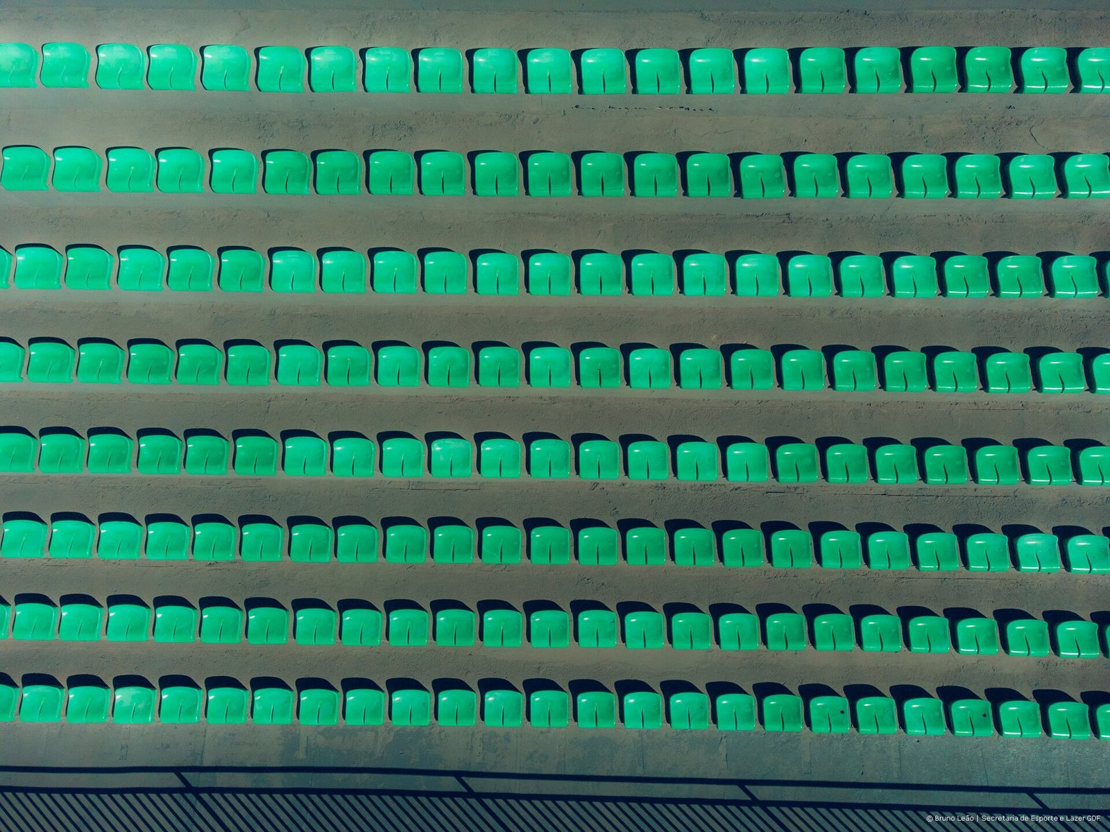 Fileiras de cadeiras verdes na arquibancada do Estádio Bezerrão, no Gama