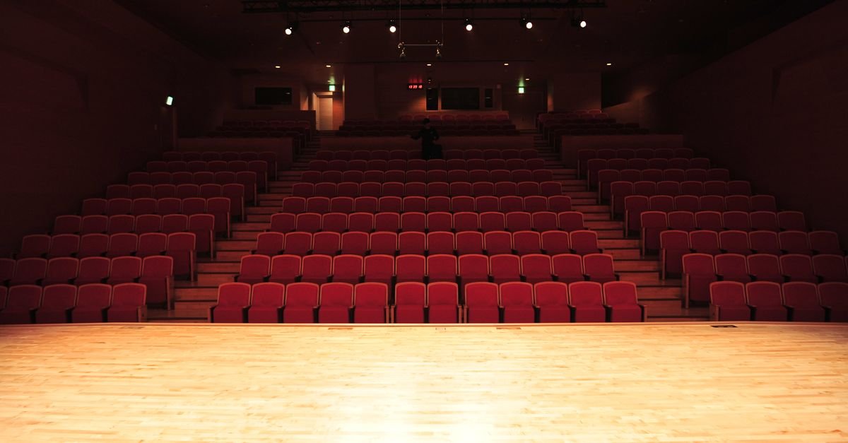 Plateia vazia de teatro com poltronas vermelhas vista a partir do palco